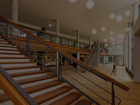 Foyer der Beethovenhalle mit breiter Treppe, Galerieebene und runden Hängelampen